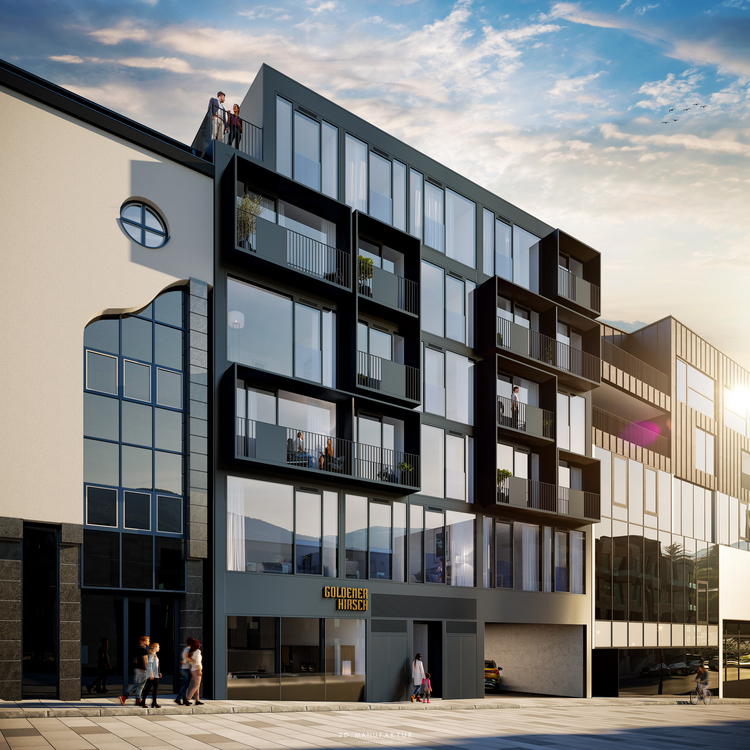 Das Bild zeigt ein modernes, mehrstöckiges Gebäude mit großen Fenstern und Balkonen. Im Vordergrund sind Menschen zu sehen, die vorbeigehen. An der Fassade ist der Schriftzug "GOLDENER HIRSCH" deutlich sichtbar. Der Himmel ist teilweise bewölkt, was auf einen späten Nachmittag hindeutet.